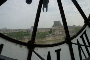 Train station clock in the shadows. With the city of Paris and the Seine in view.